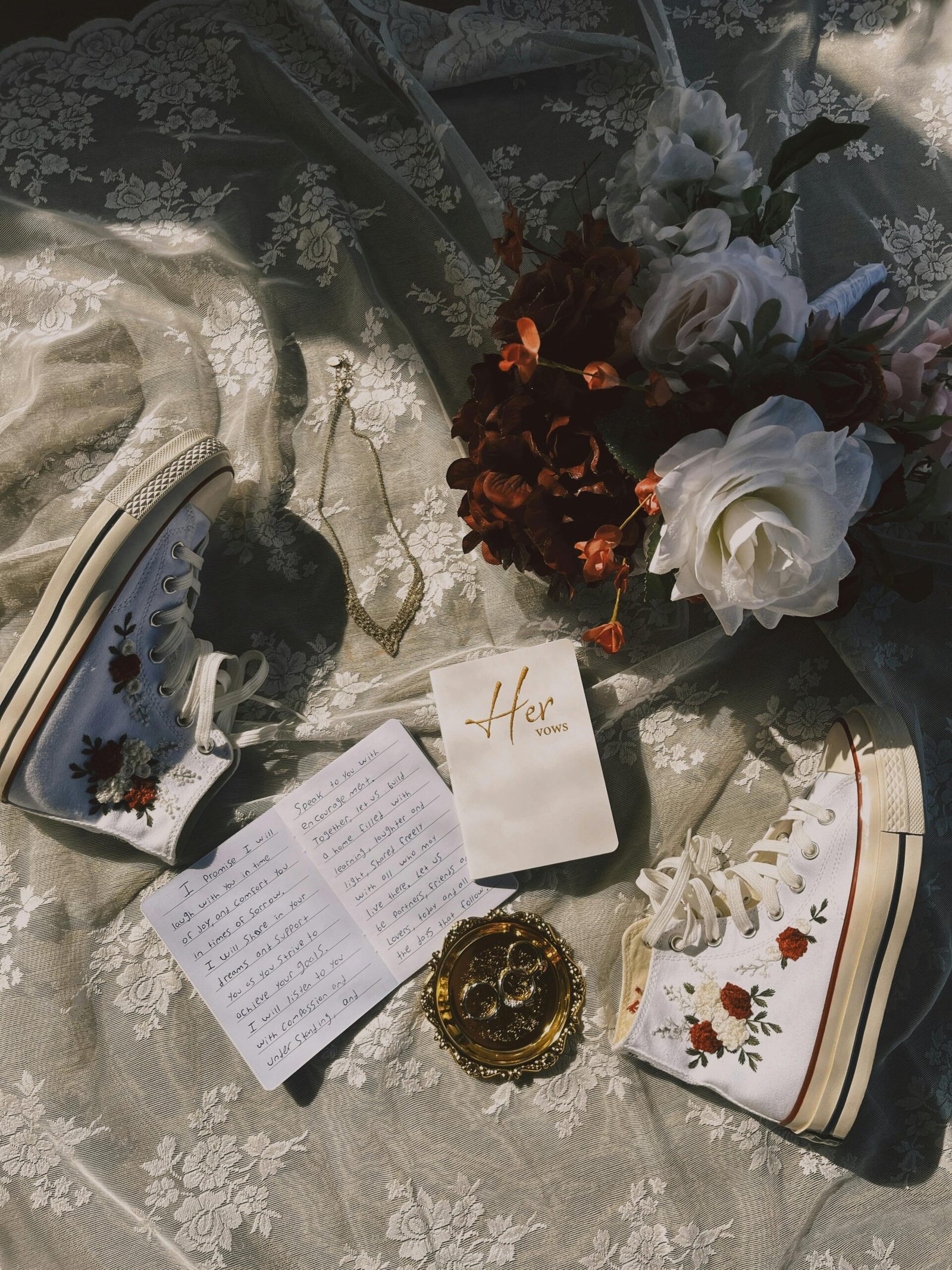 Artistic display of wedding accessories with floral sneakers on lace fabric.