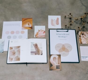 A flat lay of branding elements with color palettes and strategic planning documents on a concrete surface.